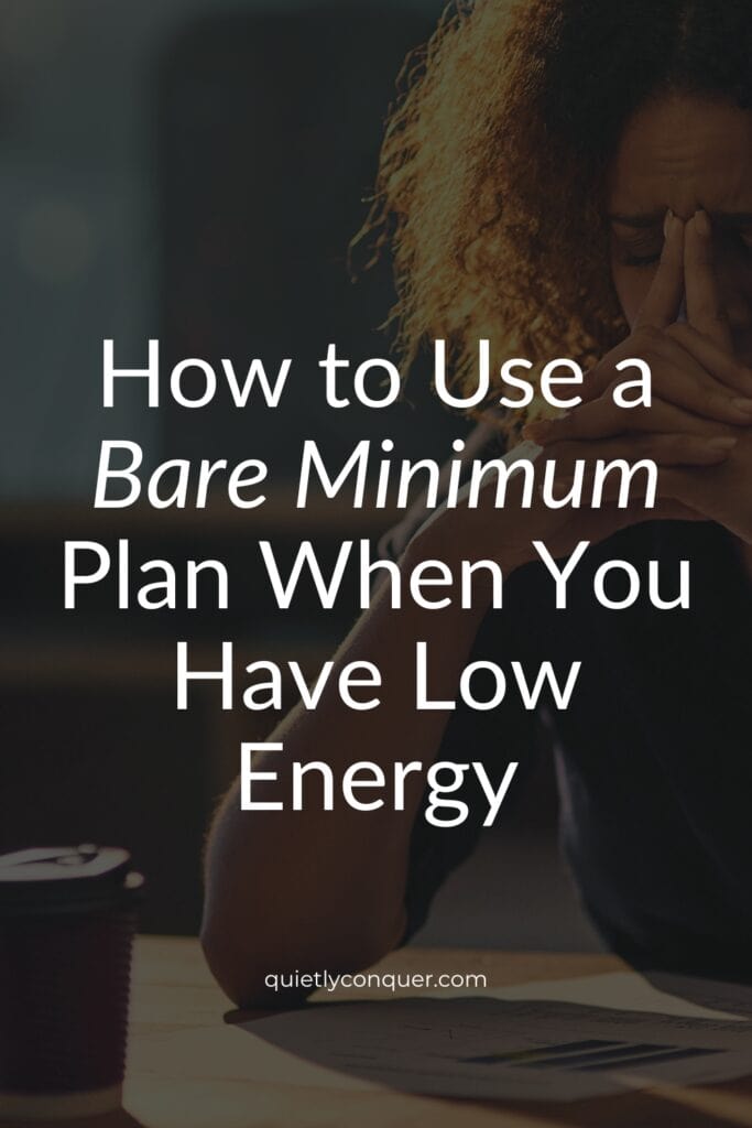 Bare Minimum Plans When Energy is Low. Woman sat at desk, head in hands coffee cup in front of her