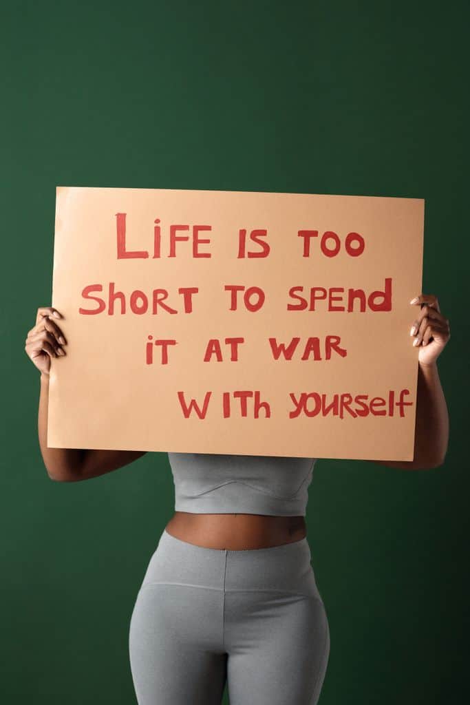self-confidence - Woman holding motivational sign about self-love and peace on green background.