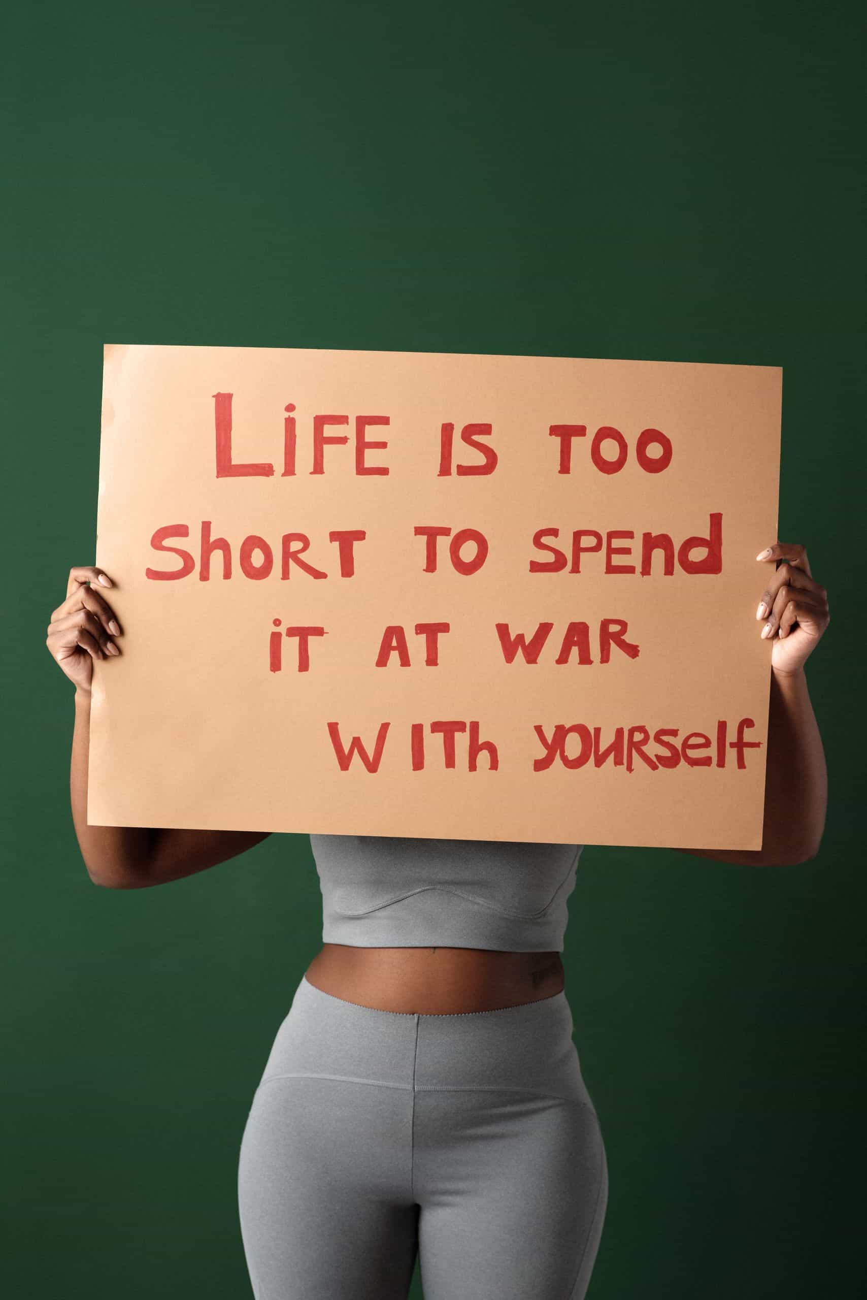 self-confidence - Woman holding motivational sign about self-love and peace on green background.
